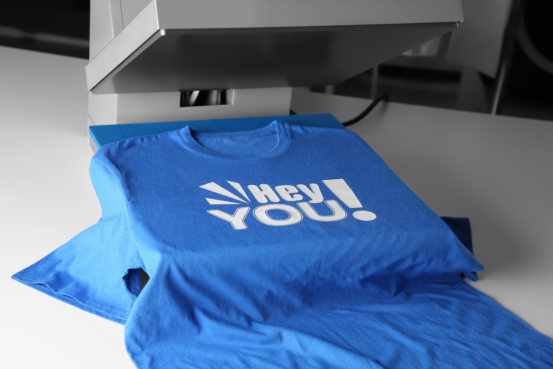 Printing logo. Heat press with blue t-shirt on white table